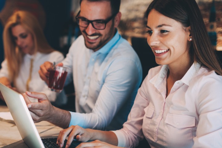 Group of people laughing in front of their computers.